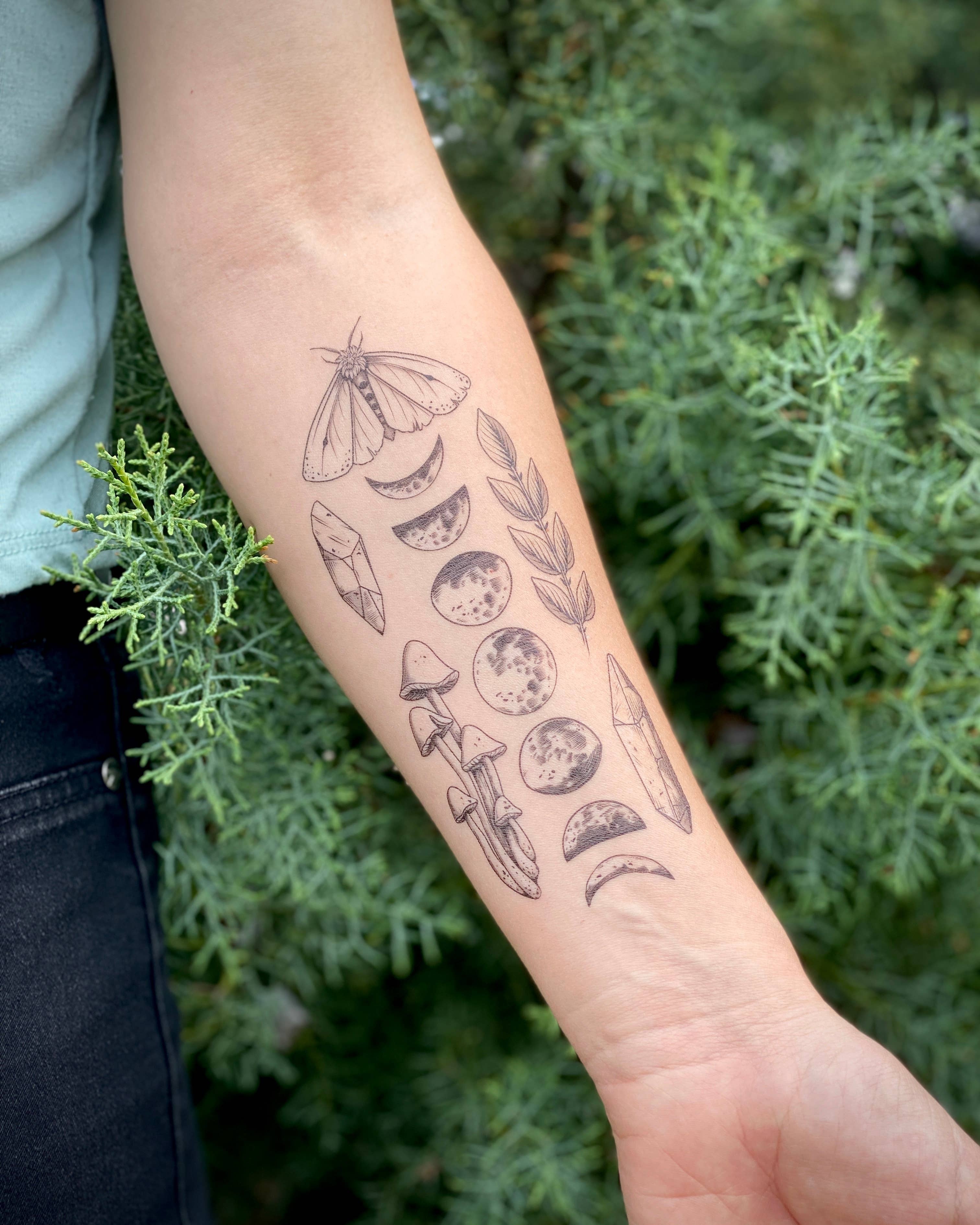 Moon Magic temporary tattoo sheet 2 pack. This temporary tattoo sheet features a long moon phase design, a slender cluster of wild mushrooms, a leafy sprig, light and fluffy small moth, and two crystal shards.

The whole sheet measures 3 by 7 inches.

All