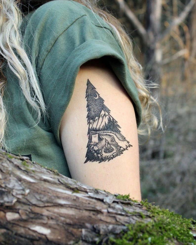 Mountain Camping temporary tattoo 2 pack. A tranquil camping scene within the shape of a pine tree. In this design, there is a sense of stillness on a chilly evening, under a starlit sky and snowcapped mountains. A river runs out through the pine forest, 