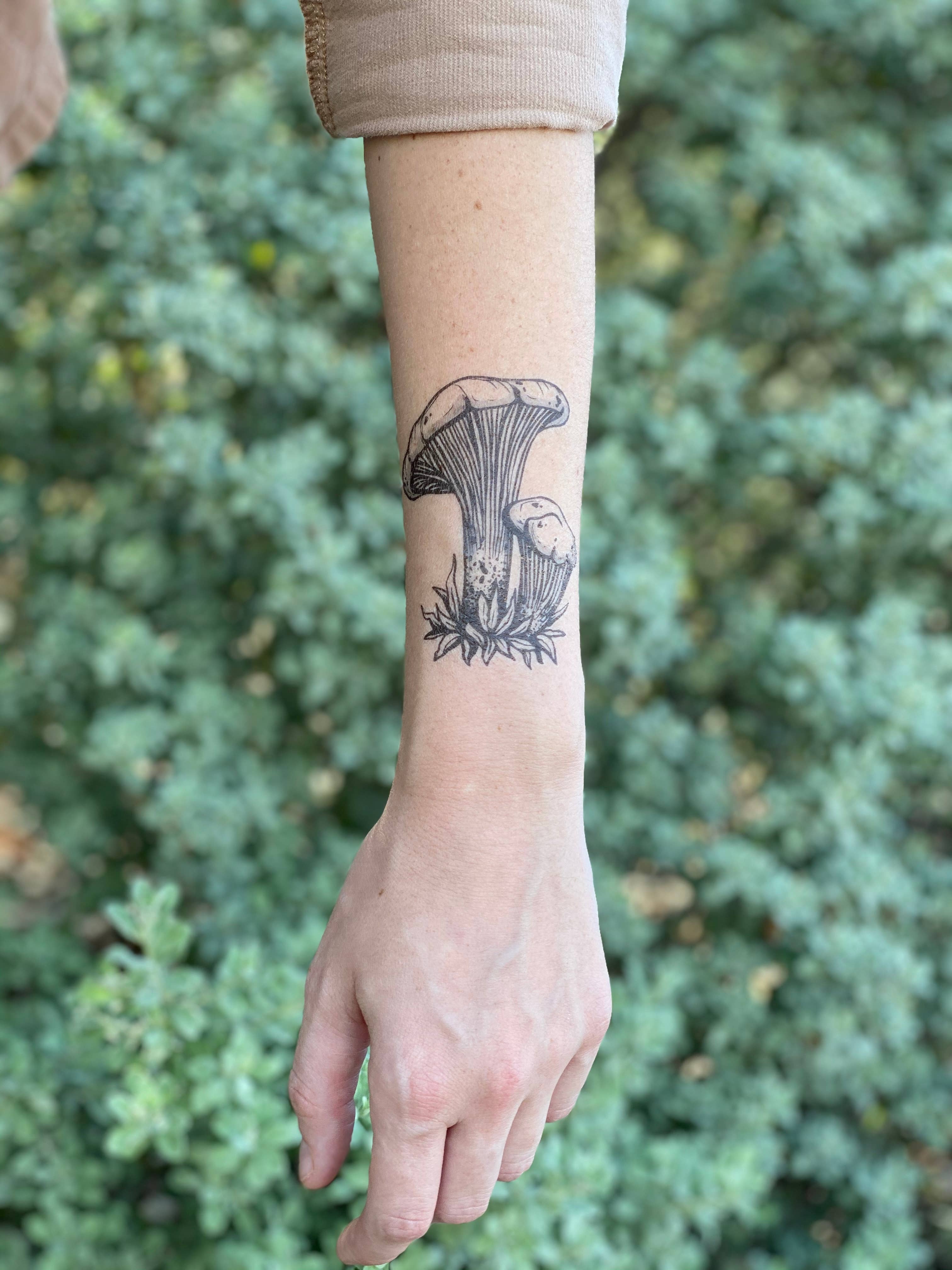 Chanterelle mushroom temporary tattoo 2 pack. Freshly plucked from the forest floor, this plump Chanterelle mushroom is a fungi forager's dream, complete with a dusting of dirt and mossy bits near the base.

She stands just over 3" tall.

All tats now com
