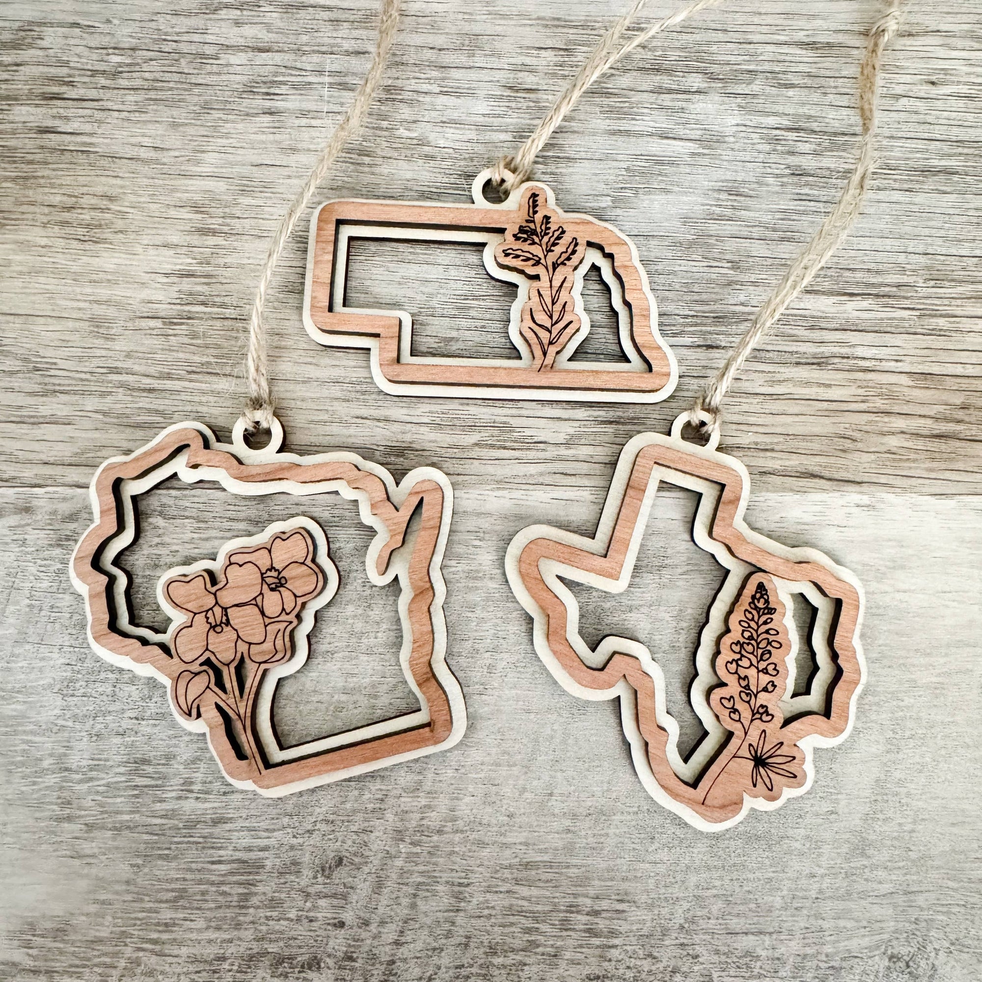 Gorgeous wooden state flower Christmas ornaments are the perfect addition to your shop this holiday season.

*All 50 States Available*

FINISHED- Every ornament is handcrafted with 2 layers of beautiful birch wood + cherry wood and finished with a silky-s