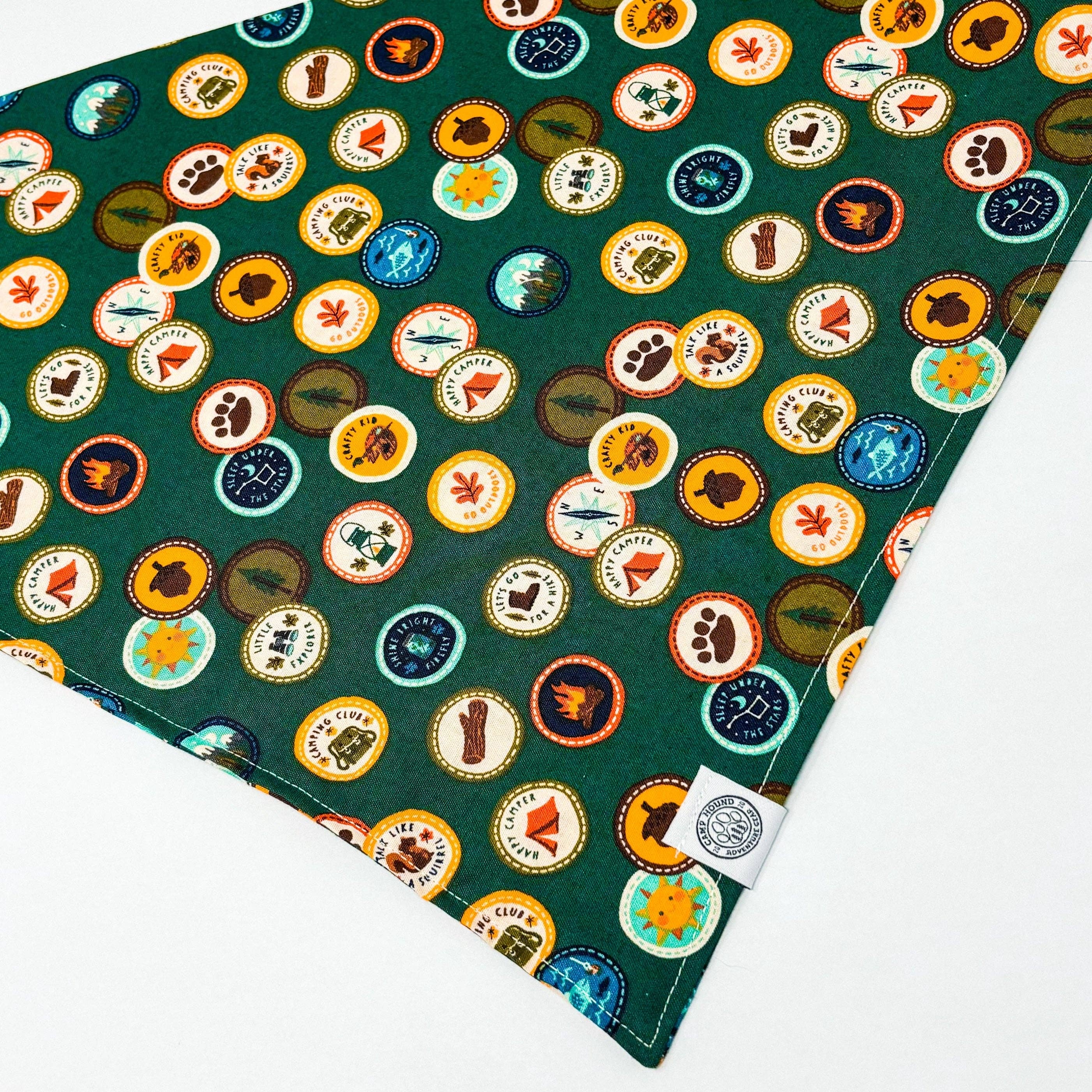 Elevate your furry friend's style with our Maverick Bandana. Made with durable cotton, this dog bandana is perfect for any outdoor adventure or backyard playtime. The forest green color and scout badges add a touch of adventurous spirit to your dog's look
